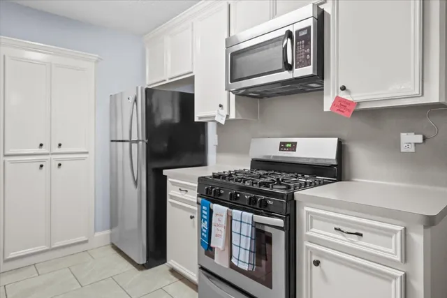 a kitchen with stainless steel appliances granite countertop white cabinets and a stove a refrigerator with wooden floor