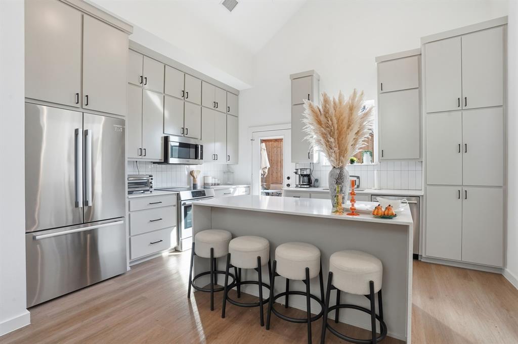 1301 Tillery Court Grapevine, TX 76051 - Photo 2 of 28 a kitchen with stainless steel appliances a refrigerator a sink dishwasher a stove and white cabinets with wooden floor
