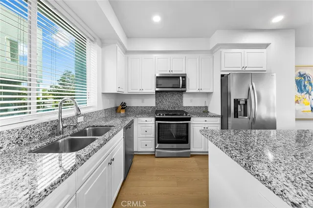 a kitchen with kitchen island granite countertop a sink stainless steel appliances and cabinets