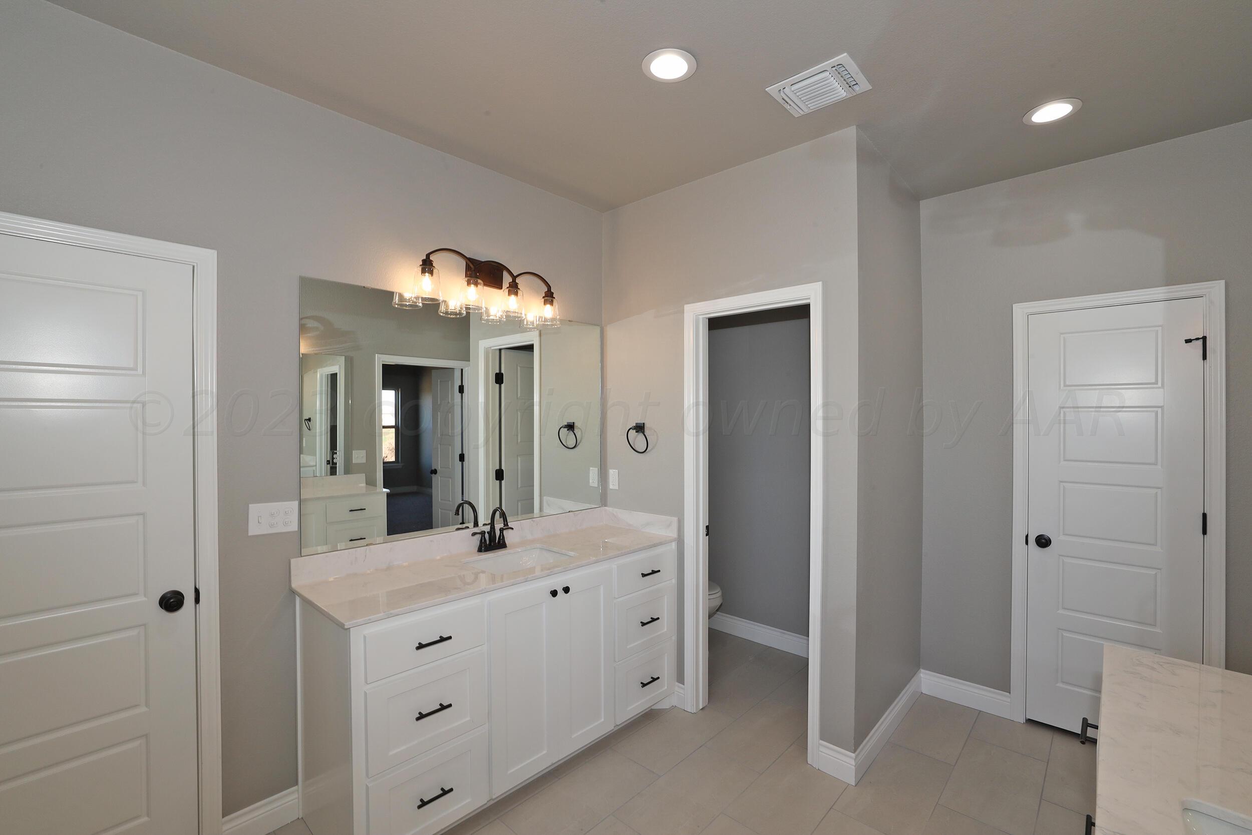 9551 Trinity Drive Amarillo, TX 79119 - Photo 17 of 46 a large bathroom with a double vanity sink a large mirror and a shower