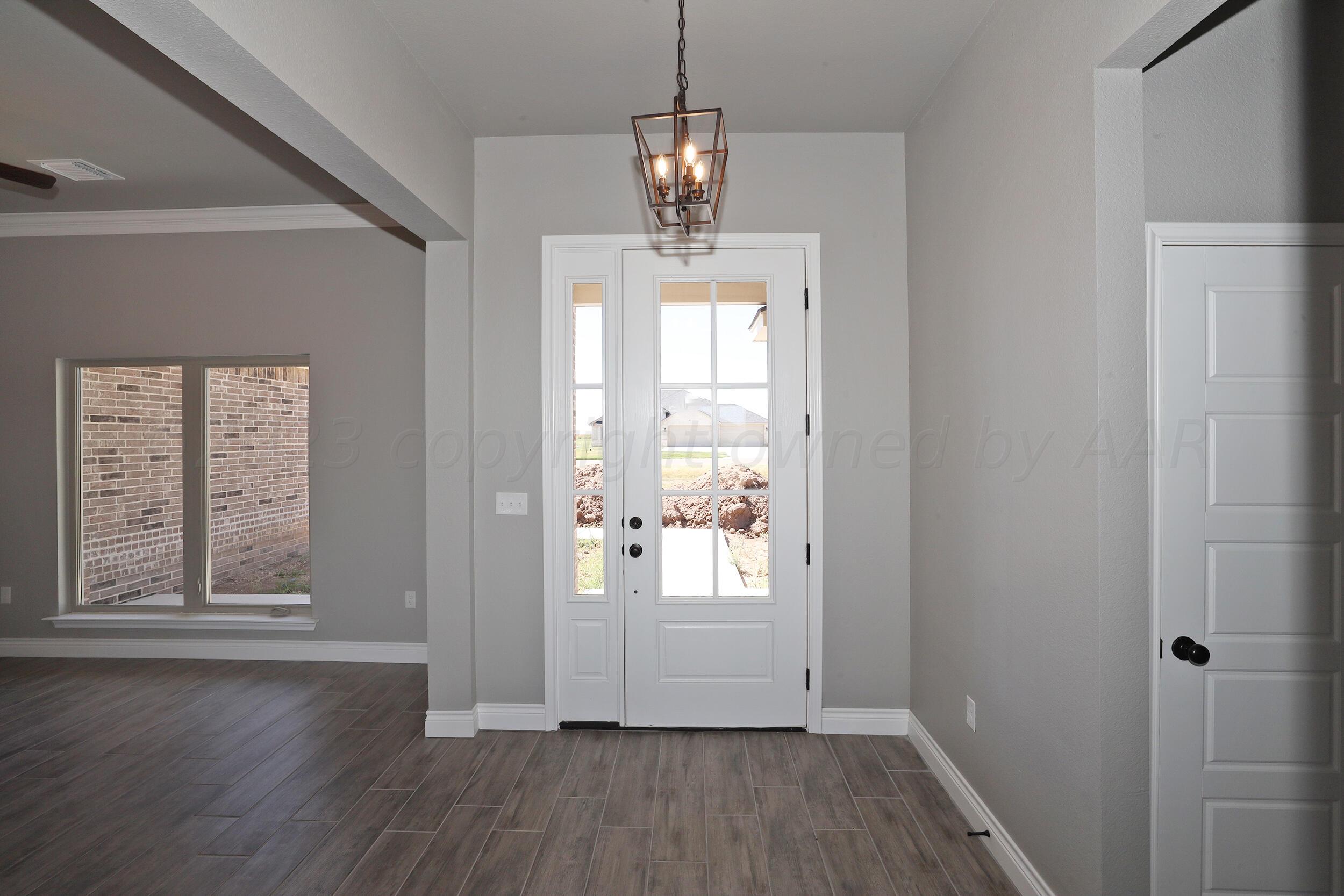 9551 Trinity Drive Amarillo, TX 79119 - Photo 32 of 46 a view of a room with wooden floor windows and chandelier