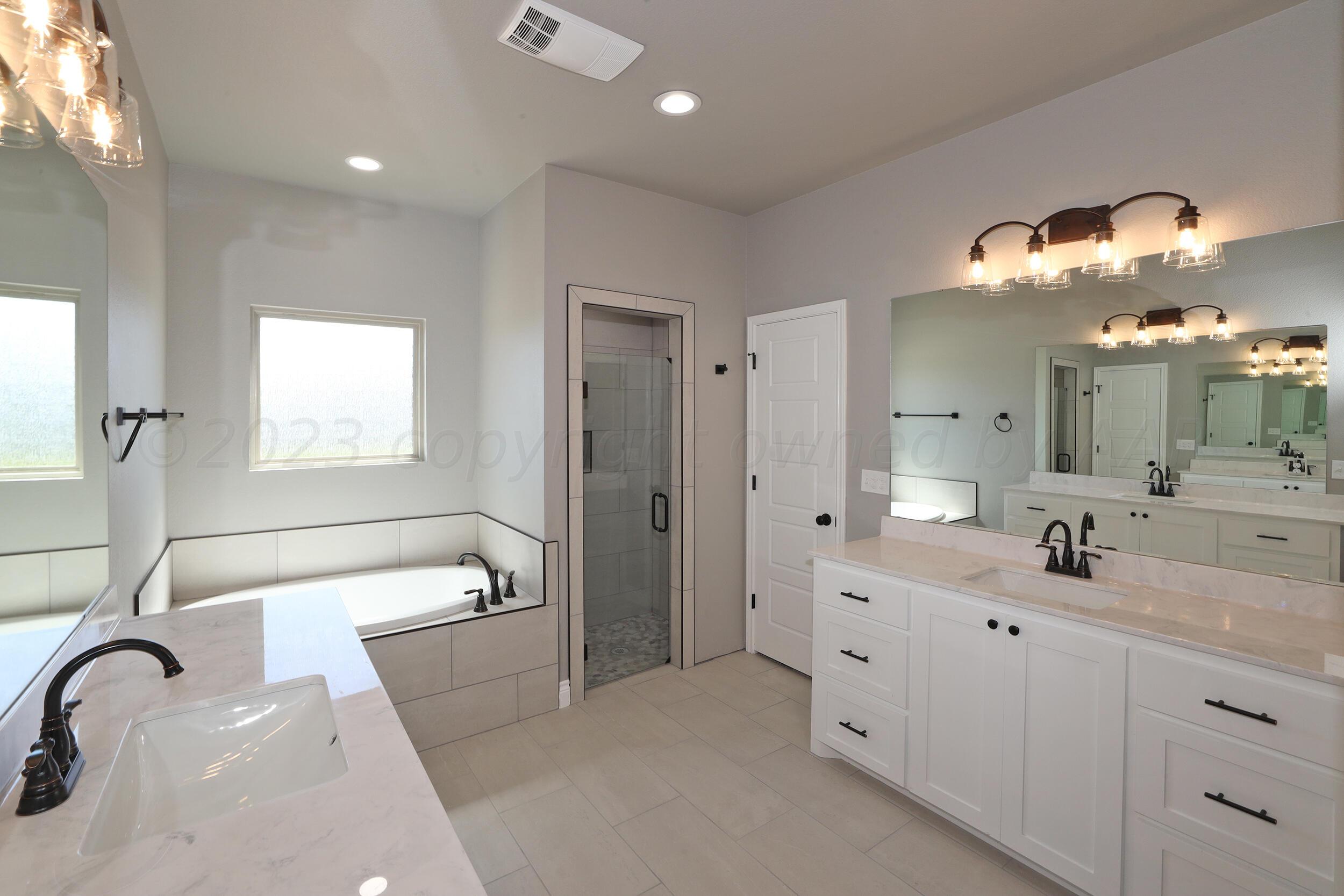 9551 Trinity Drive Amarillo, TX 79119 - Photo 10 of 46 a spacious bathroom with a double vanity sink a mirror a bathtub and window