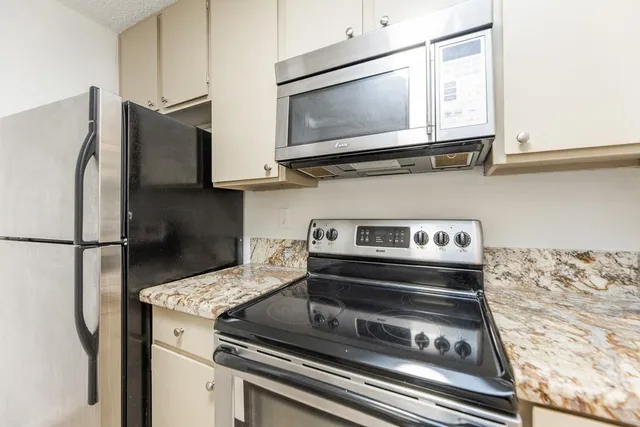 a kitchen with granite countertop a sink stove and microwave