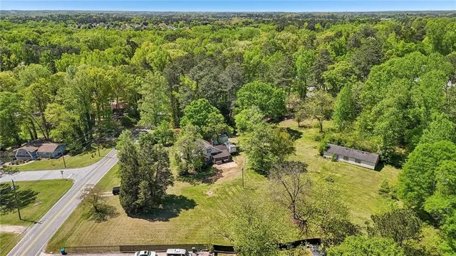 an aerial view of residential house with outdoor space and trees all around