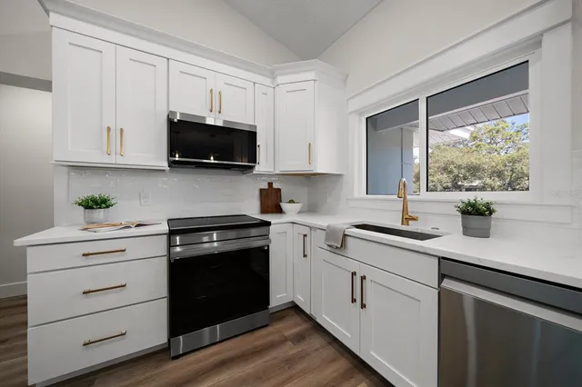 a kitchen with granite countertop white cabinets and a stove with wooden floor