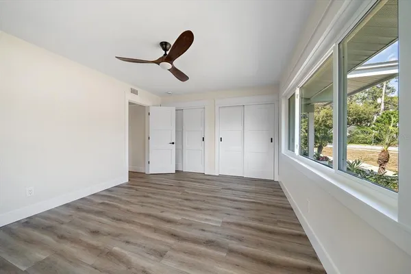 a view of empty room with wooden floor and fan