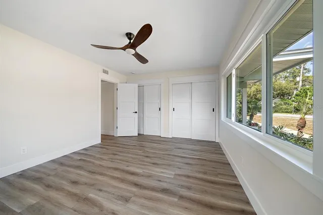 a view of empty room with wooden floor and fan