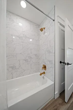 a bathroom with a white bath tub a shower and a sink