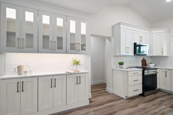 a kitchen with white cabinets and wooden floor