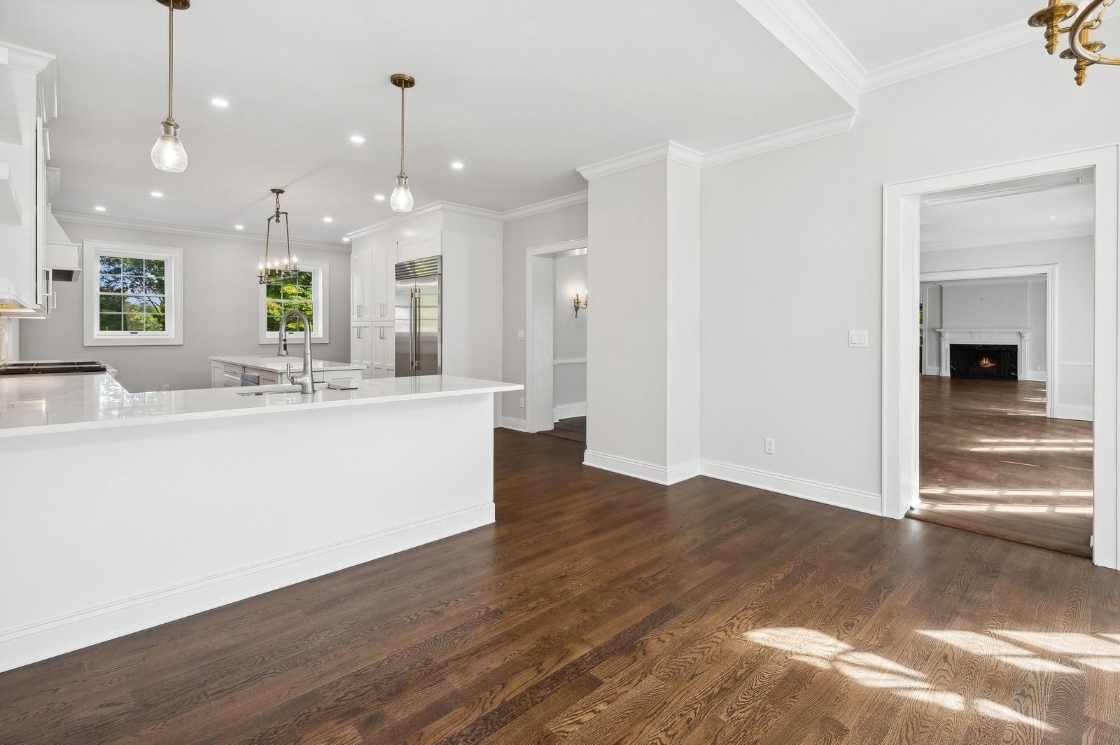45 Durham Road Bronxville, NY 10708 - Photo 18 of 25 Kitchen featuring white cabinetry, hanging light fixtures, stainless steel built in refrigerator, dark wood-type flooring, and crown molding