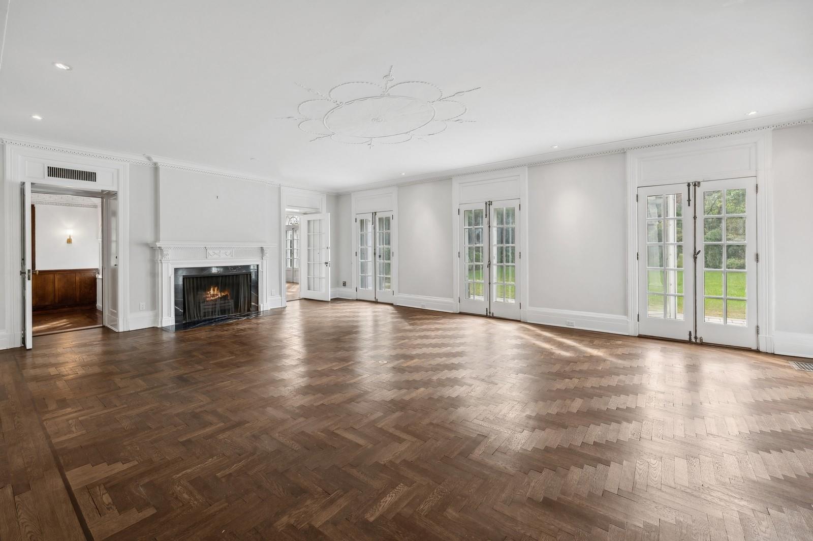 45 Durham Road Bronxville, NY 10708 - Photo 9 of 25 Unfurnished living room featuring a fireplace, ornamental molding, dark parquet flooring, and french doors