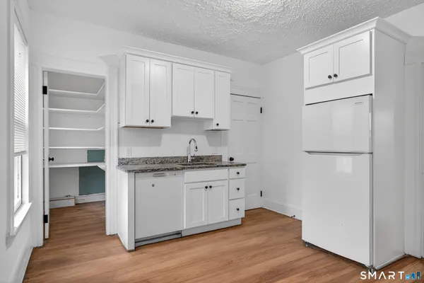 a kitchen with granite countertop white cabinets and refrigerator