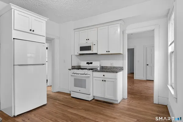 a kitchen with stainless steel appliances granite countertop a refrigerator stove and white cabinets