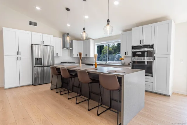 a kitchen with granite countertop a refrigerator a stove a sink a dining table and chairs