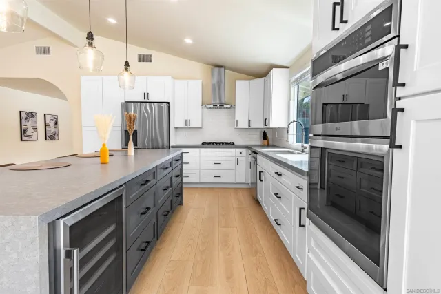 a large kitchen with stainless steel appliances sink a stove and cabinets