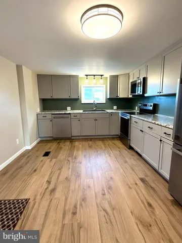 a large kitchen with a lot of counter space and wooden floor