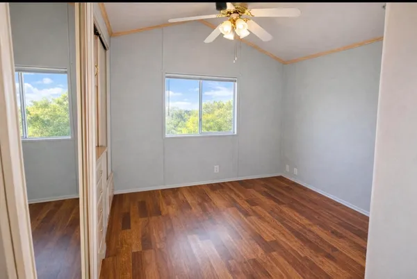 a view of an empty room with wooden floor and a window