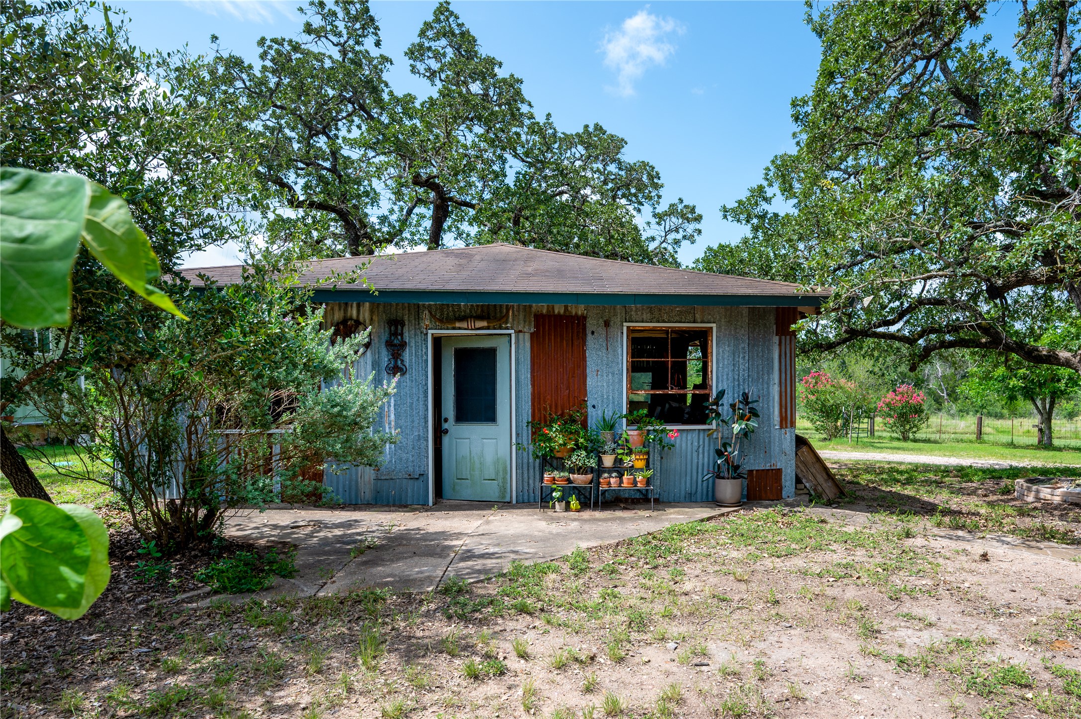 270 Dry Creek Road Manor, TX 78653 - Photo 22 of 40 A charming corrugated metal structure nestles among mature trees, offering a rustic escape.
