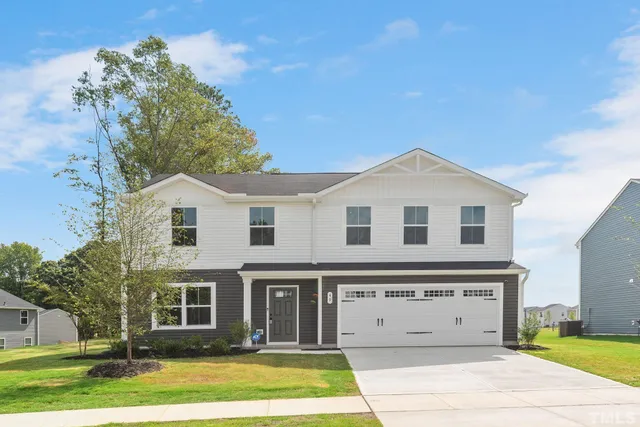 a view of a white house with a big yard plants and large trees