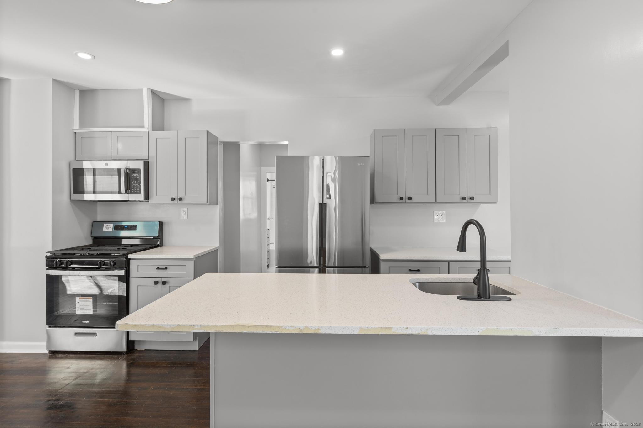 a kitchen with kitchen island a sink stainless steel appliances and cabinets