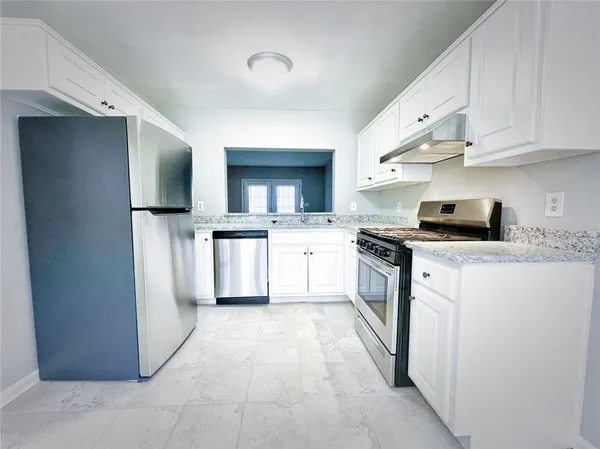 a kitchen with white cabinets and appliances