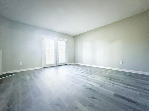 a view of an empty room with wooden floor and window