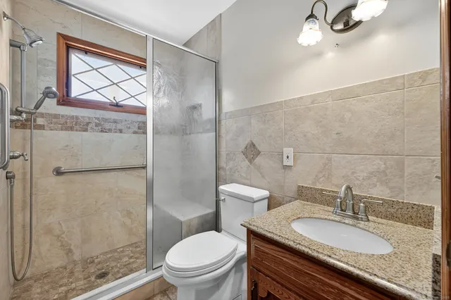 a bathroom with a granite countertop toilet a sink and a mirror