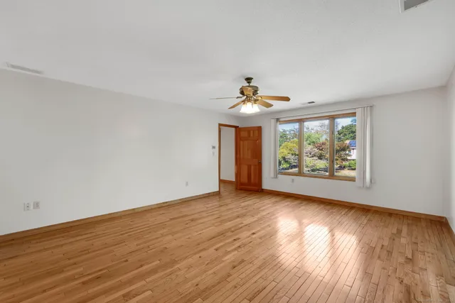 a view of an empty room with wooden floor and a window