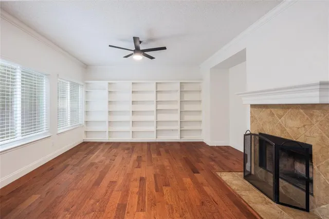 a view of an empty room with wooden floor fireplace and a window
