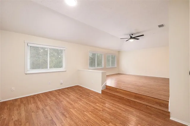 a view of a big room with wooden floor and windows