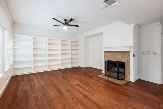 a view of empty room with wooden floor fireplace and a window