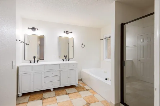 a bathroom with a double vanity sink mirror and bathtub