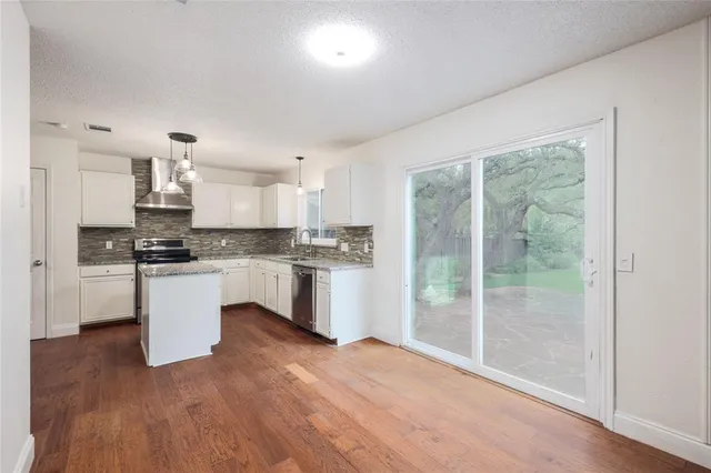 a kitchen with granite countertop white cabinets and stainless steel appliances