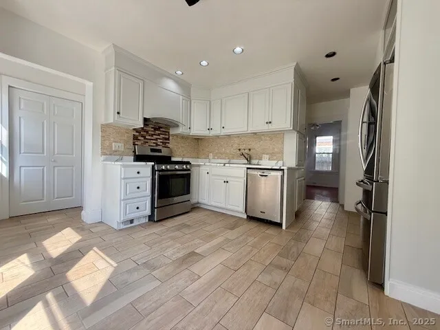 a kitchen with stainless steel appliances a sink a stove a refrigerator cabinets and a window