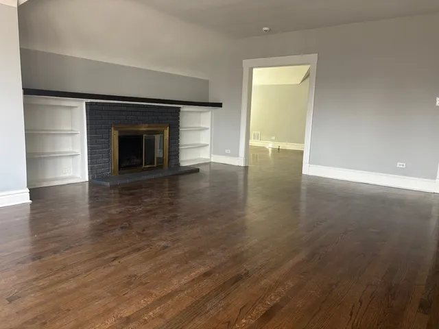 an empty room with wooden floor and a fireplace