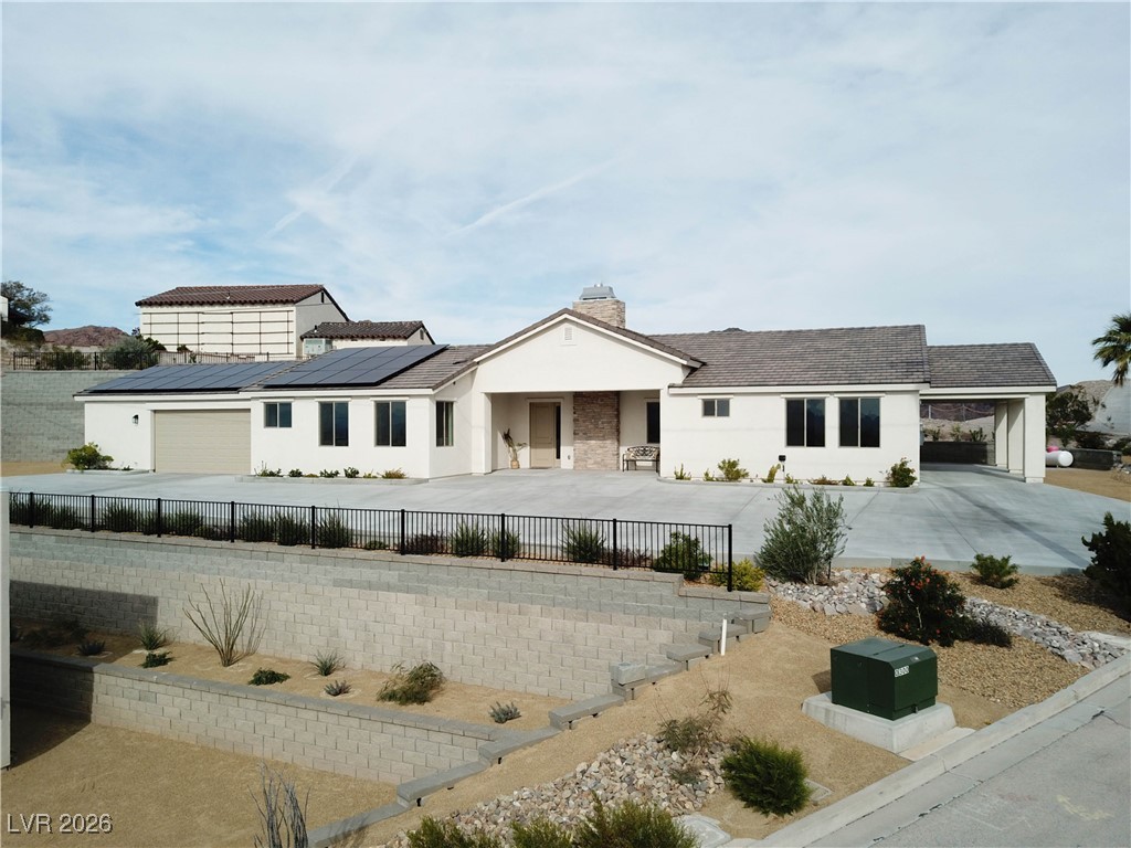 View of front of property featuring concrete driveway, a fenced front yard, stucco siding, a chimney, and a porch
