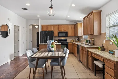a kitchen with granite countertop a table chairs microwave and cabinets