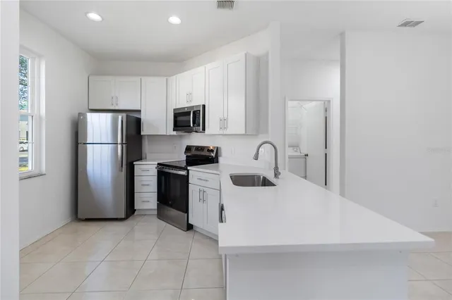 a kitchen with a sink a refrigerator and a stove top oven