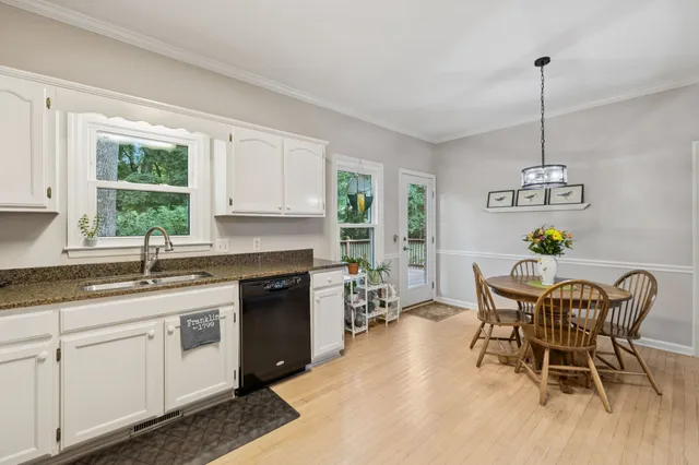 a kitchen with stainless steel appliances granite countertop a stove a sink dishwasher a dining table and chairs with wooden floor