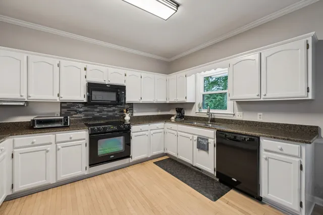 a kitchen with white cabinets appliances and a window