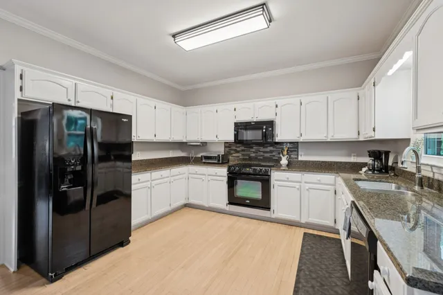 a kitchen with granite countertop a refrigerator stove and sink