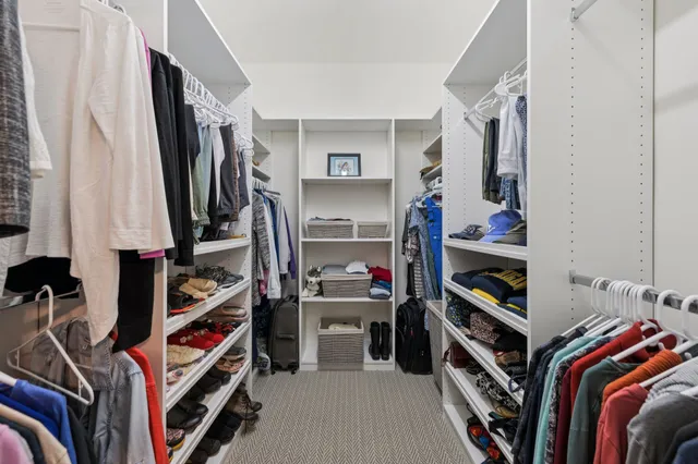 a view of walk in closet with clothes and shoes