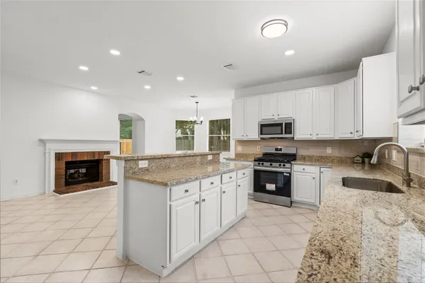 a kitchen with granite countertop a stove top oven and cabinets