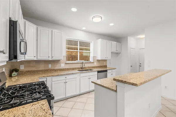 a kitchen with granite countertop a sink stove and cabinets