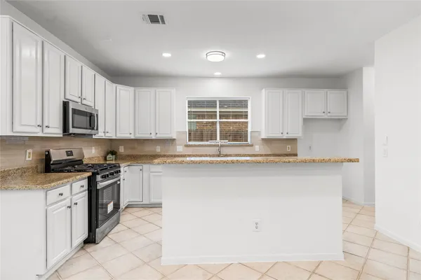 a kitchen with stainless steel appliances granite countertop a stove a sink and a microwave