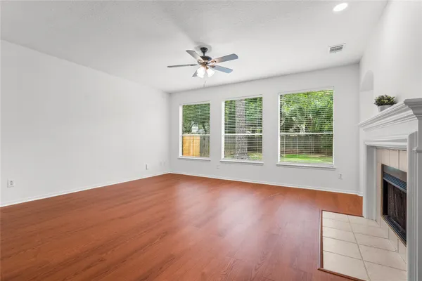 an empty room with windows fireplace and wooden floor