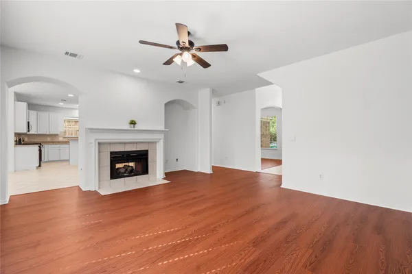 a view of an empty room with wooden floor fireplace and a window