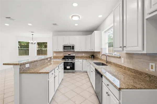 a kitchen with granite countertop stainless steel appliances a sink stove and cabinets