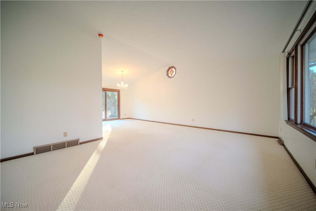 698 Albert Horning Road Atwater, OH 44201 - Photo 18 of 40 Empty room with vaulted ceiling, a chandelier, and carpet flooring
