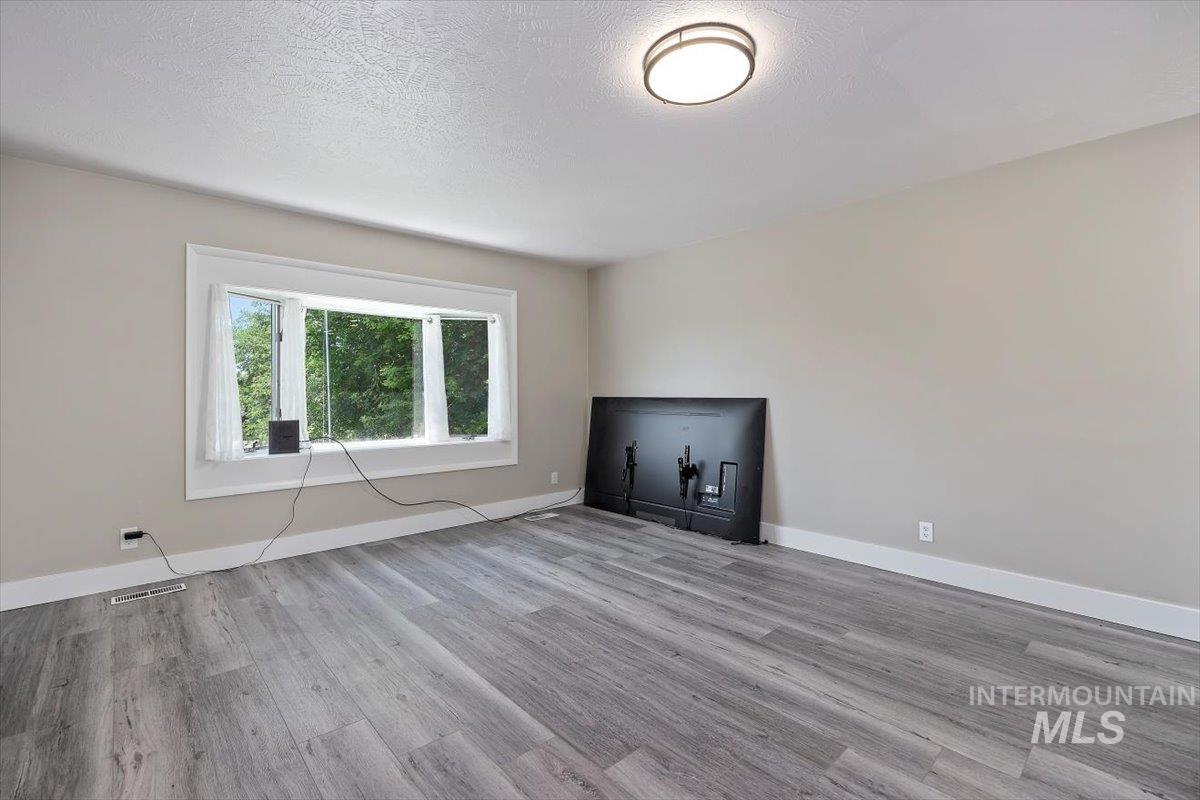 616 Doris Avenue Paul, ID 83347 - Photo 8 of 38 Unfurnished living room featuring wood finished floors and a textured ceiling